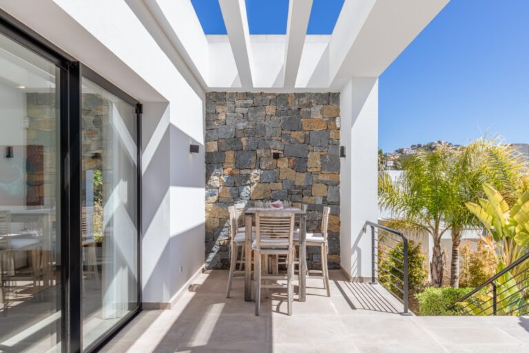 Private terrace at a modern villa in Solpark, Moraira with outdoor dining area, pergola detail, stone feature wall and open views