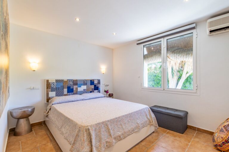 Second double bedroom inside a Mediterranean villa near Cala Baladrar in Benissa Costa with air conditioning, window, tiled floor and neutral interior