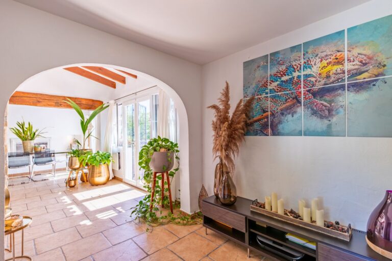 Sitting area inside a Mediterranean villa near Cala Baladrar in Benissa Costa with arched doorway, decorative wall art, indoor plants and natural light