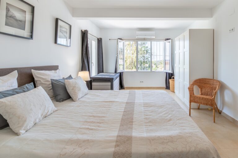 Spacious bedroom inside a renovated Mediterranean villa in Moraira with double bed, large windows, seating area and bright neutral interior