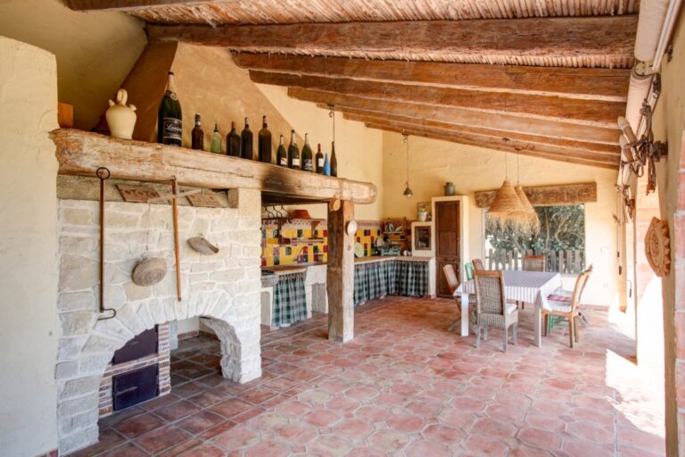 Summer kitchen at a rustic Mediterranean estate near Moraira with barbecue area, tiled terrace, exposed beams and traditional outdoor dining space
