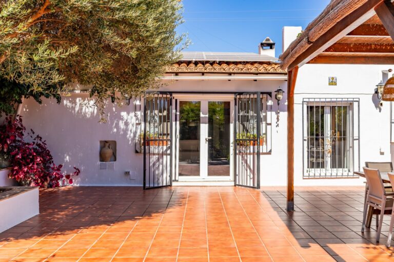 Terrace entrance at a Mediterranean villa near Cala Baladrar in Benissa Costa with tiled outdoor area, white exterior walls, garden planting and covered dining space