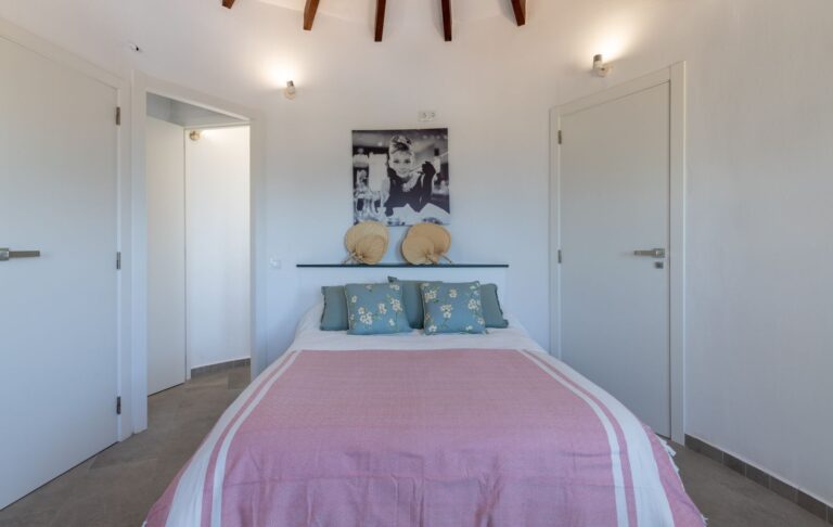 Tower bedroom inside a renovated Mediterranean villa near Cala Baladrar in Benissa Costa with exposed ceiling beams, double bed and bright windows