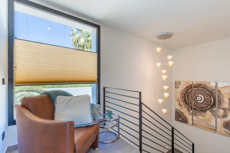 Upper landing inside a modern villa in Solpark, Moraira with seating area, large window, stair railing and bright contemporary interior