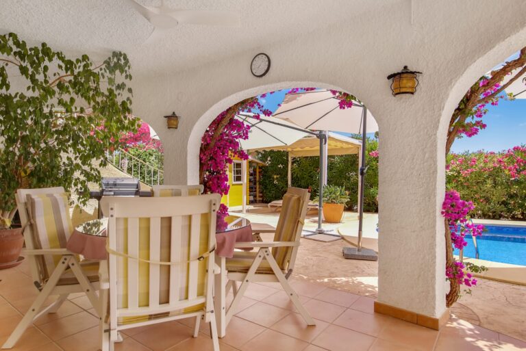 Covered terrace with arches overlooking the pool and garden at a sea view villa in Calpe