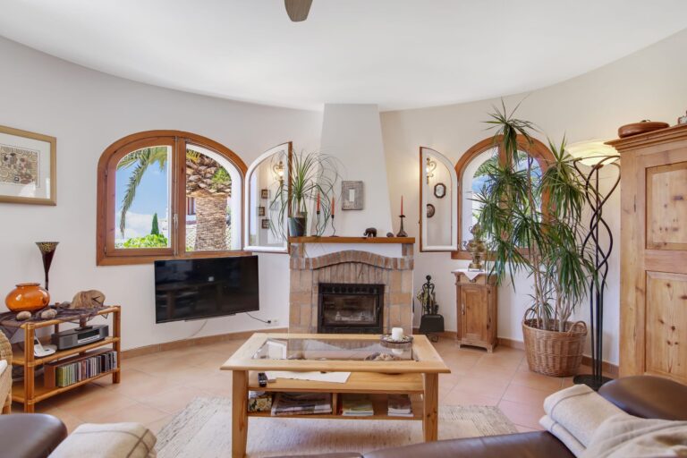 Living room with fireplace and arched windows at a sea view villa in Calpe